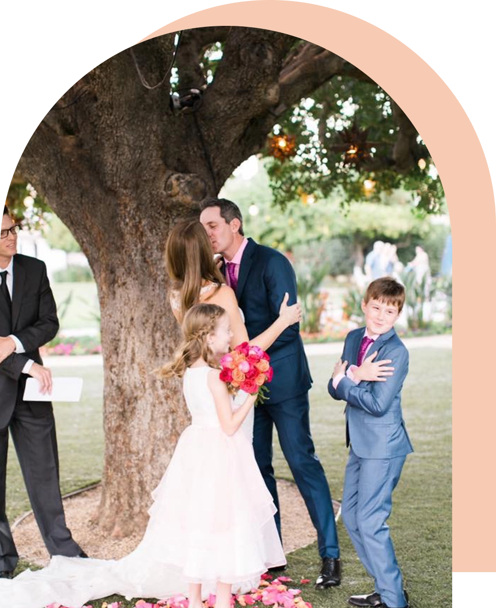 A young couple kissing under the tree with two children.